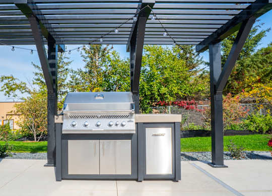 A modern outdoor kitchen setup with a grill, sink, and cabinet.