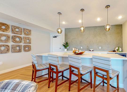 A kitchen with a white counter and wooden chairs.