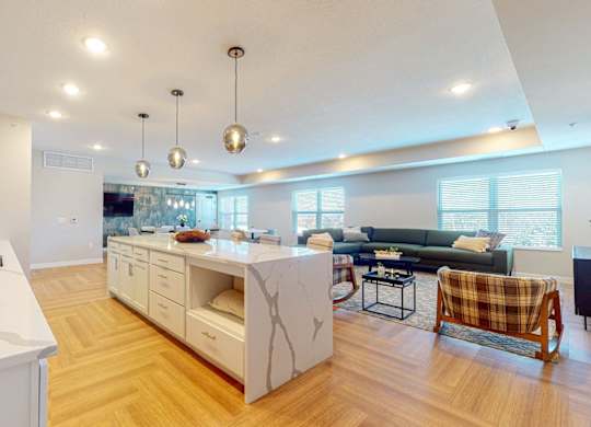 A modern kitchen with a white countertop and wooden flooring.