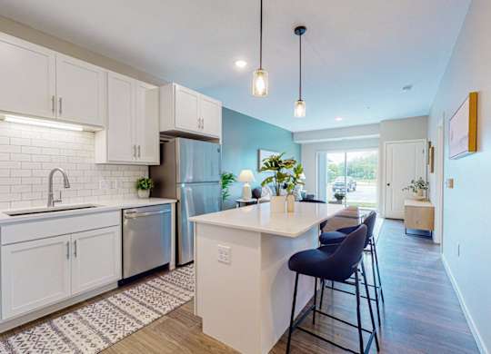 A kitchen with white cabinets and a blue chair.