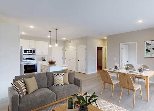A modern living room with a grey couch and a dining table set for four.