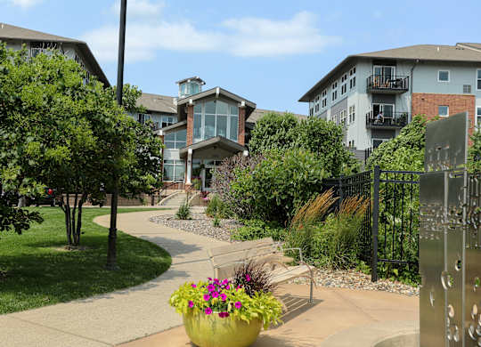 a walkway with benches and buildings in the background