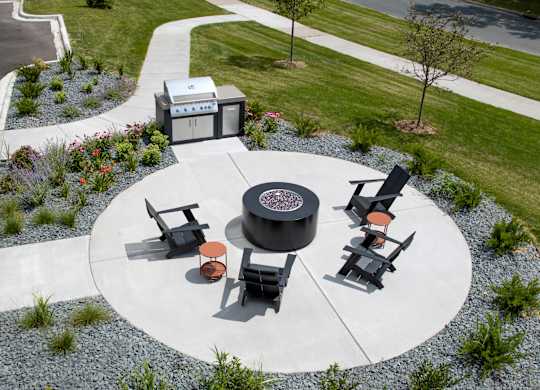 a fire pit and seating area on a concrete patio in a park