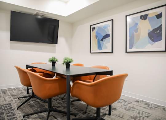 a meeting room with a table and chairs and a tv on the wall