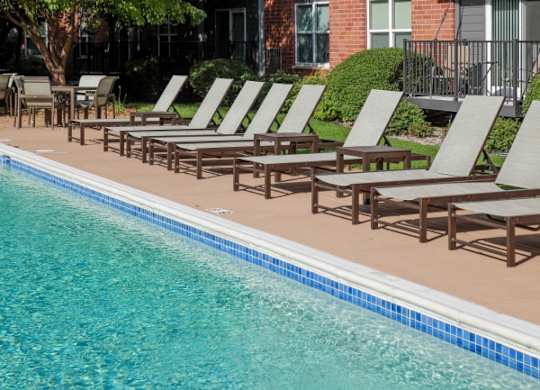 A pool with chairs and a building in the background.
