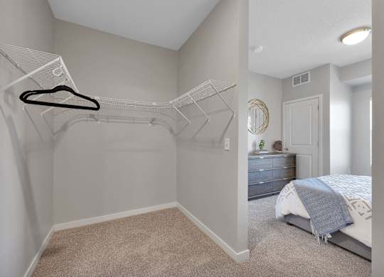 A bedroom with a bed, dresser, and a hanger on the wall.