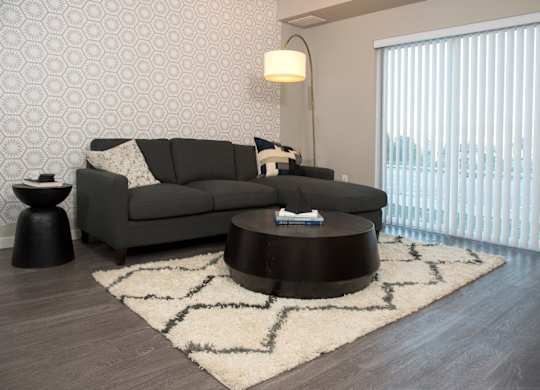 A grey couch with a white pillow is in front of a wallpapered wall.