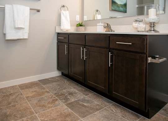 A bathroom with a brown cabinet and a tiled floor.