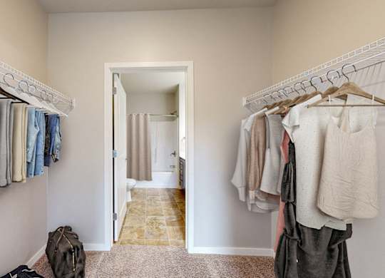 A hallway with clothes hanging on both sides and a bag on the floor.