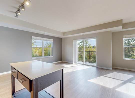 A spacious room with a table and chairs in the foreground and sliding glass doors leading to a balcony.