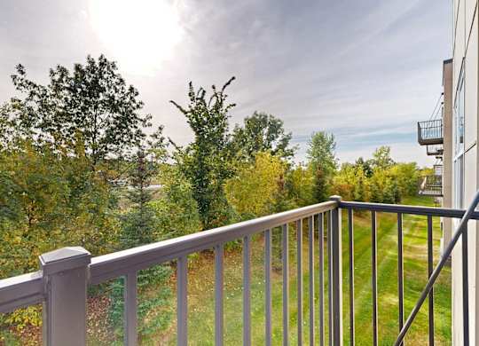 A balcony with a metal railing overlooks a green landscape.