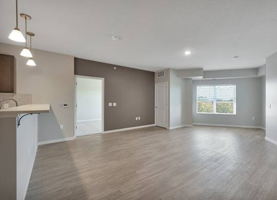 A spacious living room with a kitchenette and a view of the outdoors.