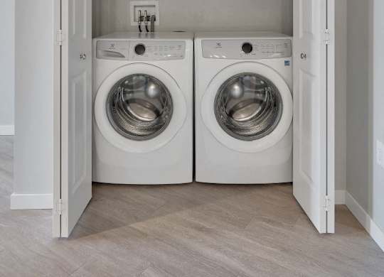 A laundry room with two washing machines and a white door.