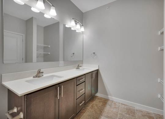 A bathroom with a sink, mirror, and lighting fixtures.