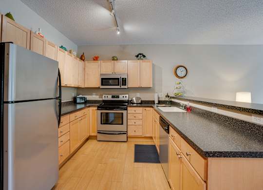 A kitchen with wooden cabinets and black countertops.