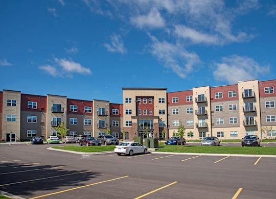 A parking lot in front of a multi-story apartment building.