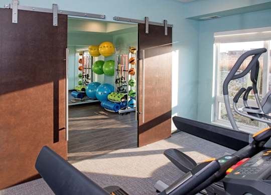 A gym with a treadmill, exercise balls and a mirror.