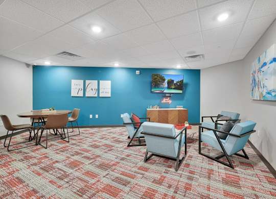 A room with a blue wall and a carpet with a red and beige pattern.