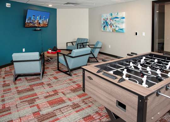 A foosball table is in the middle of a room with two chairs and a television.