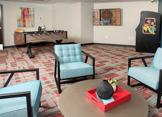 A room with a foosball table and two chairs.