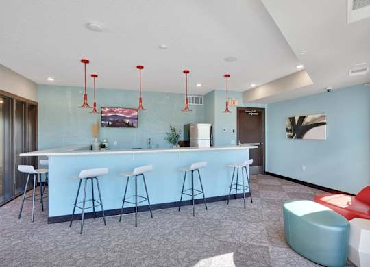 A bar area with white stools and a counter.