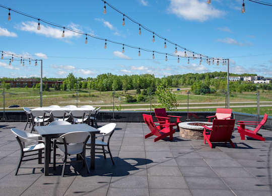 A patio with a table and chairs and string lights.
