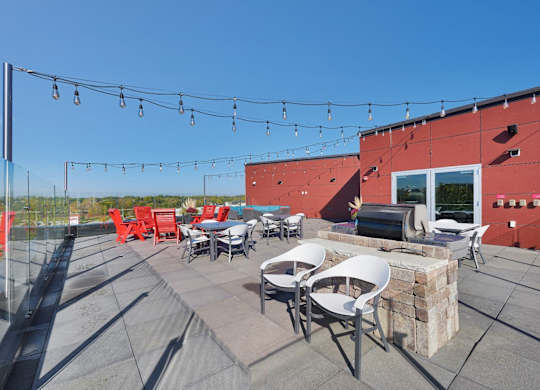 A patio with red chairs and tables is set up on a rooftop.