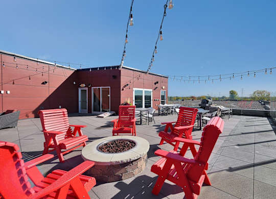 A patio with red chairs and a fire pit.