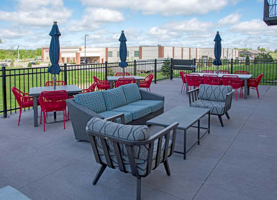 A patio with red chairs and blue umbrellas.