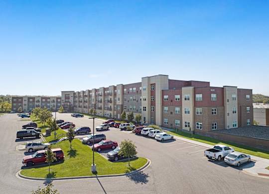 A parking lot in front of a large apartment building.