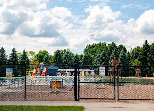 A playground with a fence and a sign in the background.
