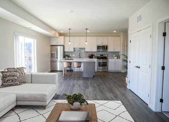 a living room and kitchen with white cabinets and a white couch