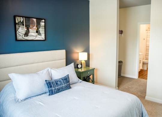 A bed with a white sheet and two pillows in a room with blue walls.