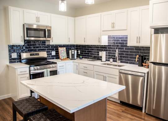 A kitchen with a white countertop and stainless steel appliances.