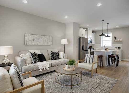 A modern living room with a grey sofa, a coffee table, and a dining area in the background.
