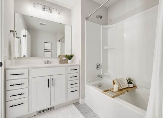 A white bathroom with a large mirror and a bathtub.