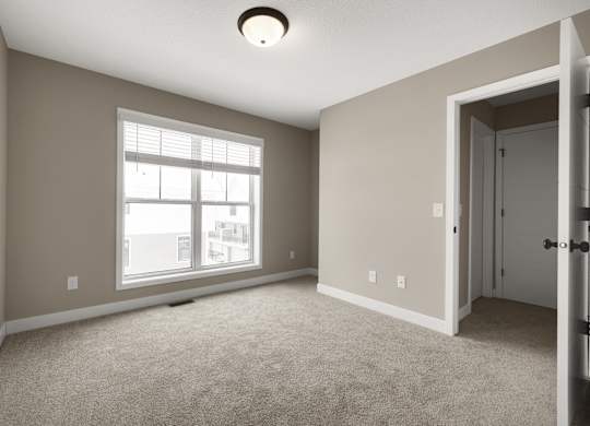 A room with a carpeted floor, a window, and a door.