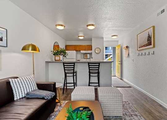 A living room with a brown leather couch and a gold floor lamp. at Vivo Toledo Apartments, Toledo, OH