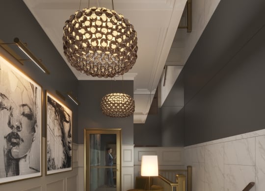 a lobby with a chair and a lamp and a staircase