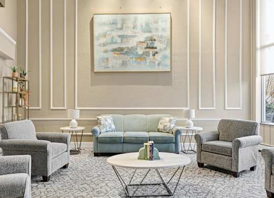 A living room with a grey couch, a green couch, and a painting on the wall.