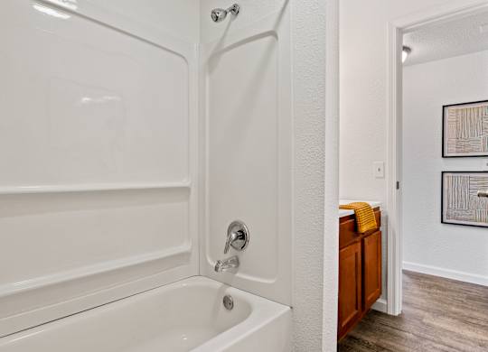 A white bathtub with a shower head and a wooden cabinet. at Vivo Toledo Apartments, Toledo, 43607