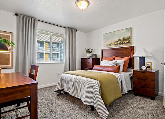 A bedroom with a bed, nightstand, and chair. at Vivo Toledo Apartments, Toledo, Ohio