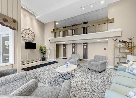 A living room with a grey sofa, a white coffee table, and a television on the wall.