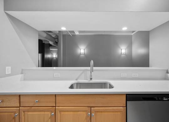 A modern kitchen with a white countertop and wooden cabinets.
