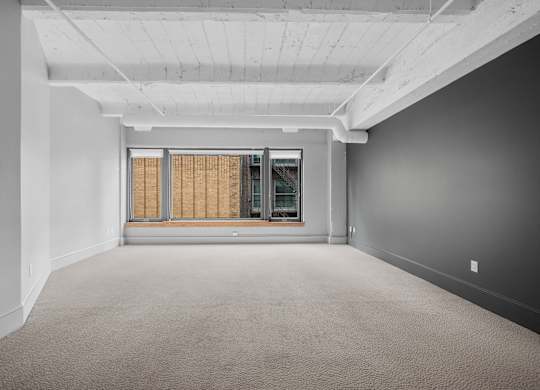 A large, empty room with a window covered in blinds.