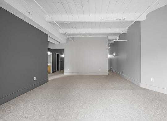 A large, empty room with grey walls and a carpeted floor.