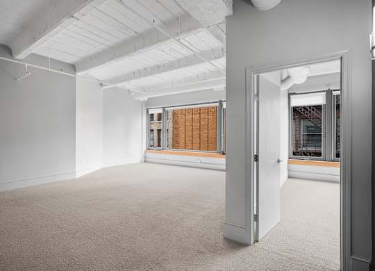 A room with a carpeted floor and a doorway leading to another room.