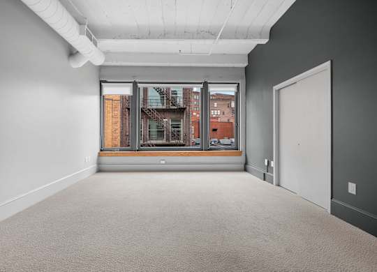 A large empty room with a view of a building outside through a window.