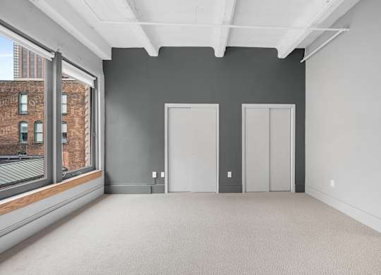 A large empty room with grey walls and carpeted floor.