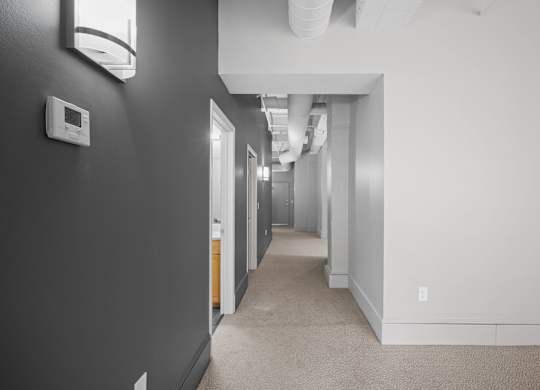 A long hallway with doors on both sides and a light on the wall.